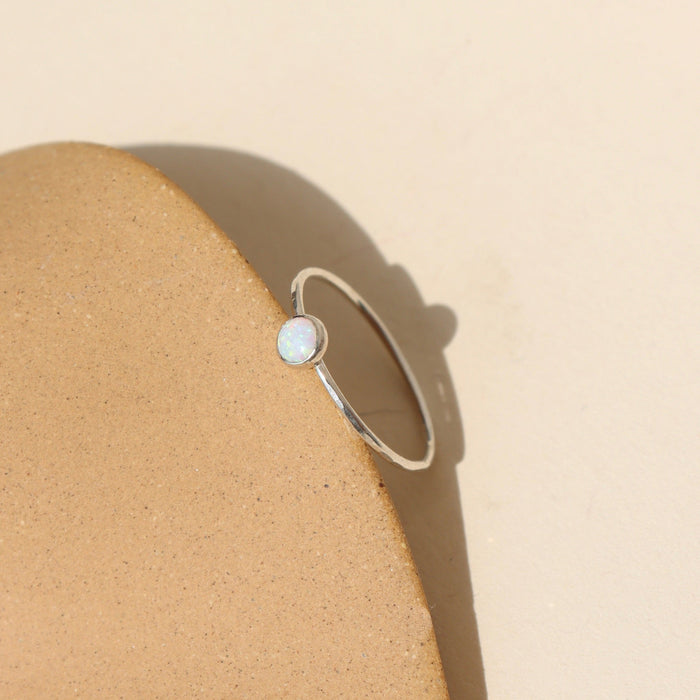 sterling silver bezel ring setting with delicate 4mm opal stone near a dish