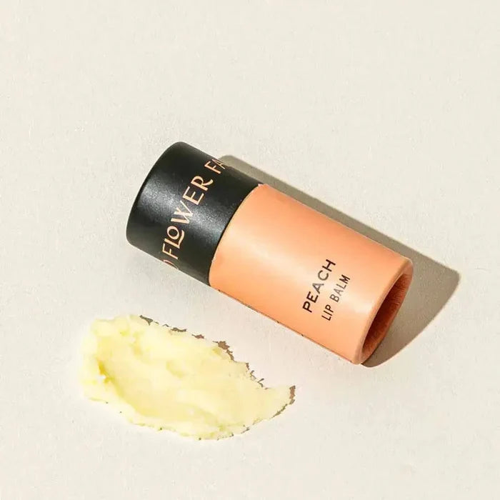 Flower Beauty peach lip balm on a beige background