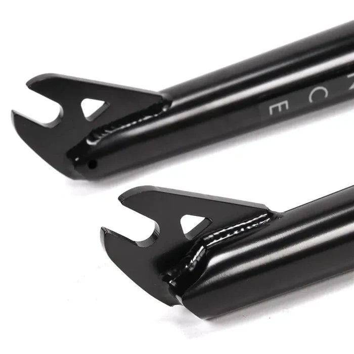 Close-up of two black heat-treated chromoly Primo Balance Fork dropouts with open slots and triangular cutouts on a white background, designed for a street fork with a 25mm offset.