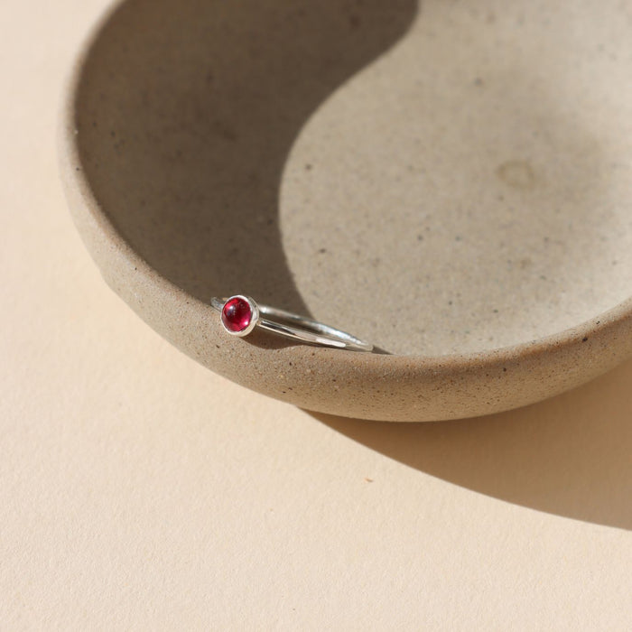 sterling silver bezel ring with 4mm ruby gemstone on a light dish