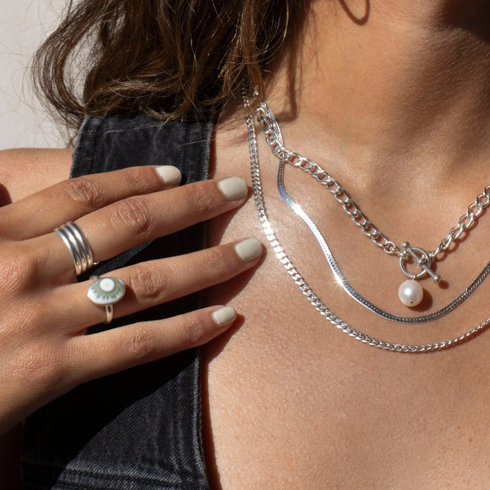 Model wearing sterling silver jewelry with a pearl and an oval ocean jasper stone