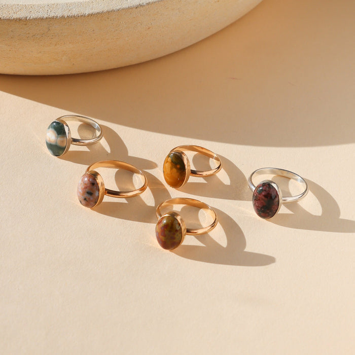 sterling silver and 14k gold fill rings with oval ocean jasper stones on a light surface