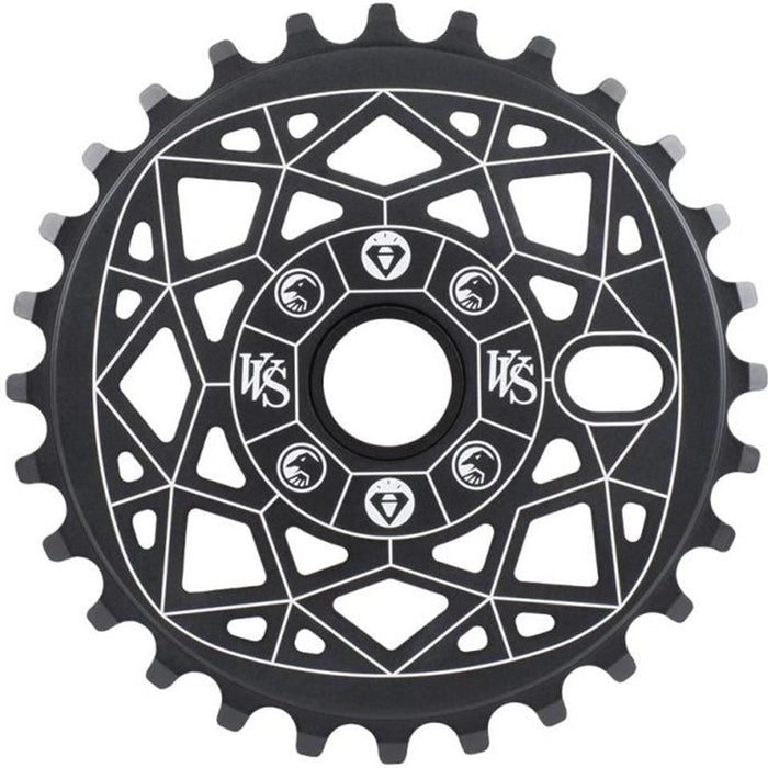 The Shadow VVS Sprocket is a black chainring made from 7075 alloy, adorned with white geometric patterns and symbols.