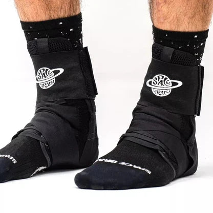 Close-up of a person wearing the Space Brace Ankle Brace V1 over black socks with a white "Space Brace" logo, standing on a white background.