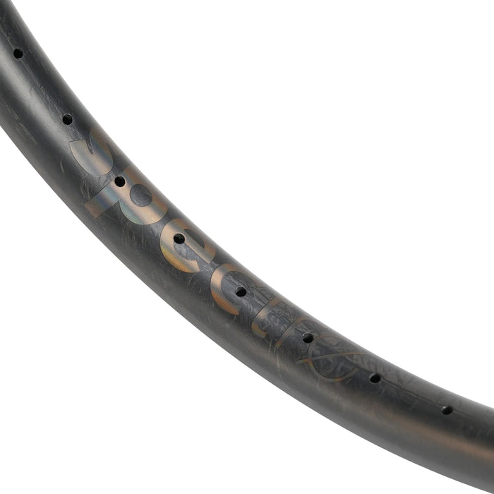 Close-up of a black Spectre V3 Lite Carbon Fiber 20 Inch 36H Brakeless Rim, crafted from premium T800 carbon fiber with spoke holes and partially visible reflective lettering on a white background. This lightweight brakeless bike rim blends strength and sleek aesthetics, making it ideal for performance-oriented cyclists.