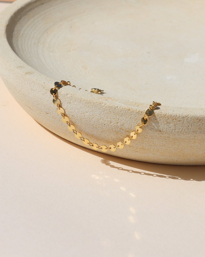 Starlight Bracelet featuring polished disc chain links styled on a textured ceramic form in natural light.