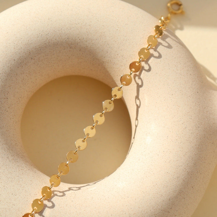 Starlight Bracelet featuring polished disc chain links styled on a textured ceramic form in natural light.