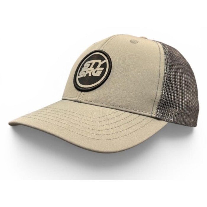 Staystrong Legacy Cap: Khaki and black trucker hat featuring a mesh back and a circular embroidered logo on the front panel.