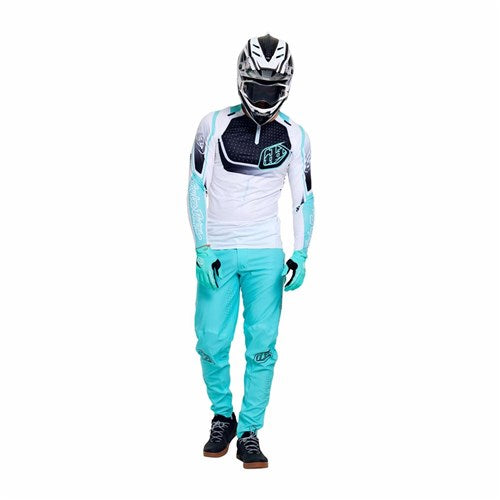 Person wearing a TLD 26.1 Sprint Ultra Jersey in Proton White, along with a helmet, gloves, chest protector, and pants, stands against a plain white background.