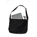 The V1da Everything Messenger Bag in black, shown on a white background, features a minimalist design with a partially visible laptop and keys tucked into one of its pockets.