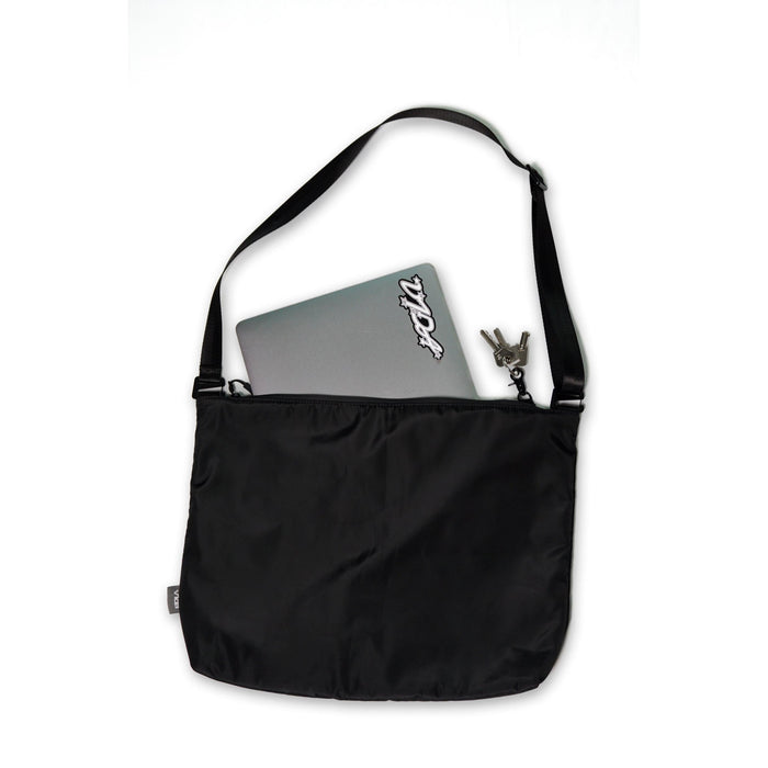 The V1da Everything Messenger Bag in black, shown on a white background, features a minimalist design with a partially visible laptop and keys tucked into one of its pockets.