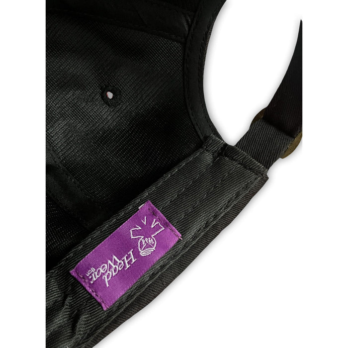 Close-up of the V1da The Dad Cap, a black unstructured hat with a purple stitched label featuring a white "HOOD WOOD" graphic and the word "BASK.