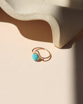 14k gold fill ring with point and round turquoise stone on a light dish