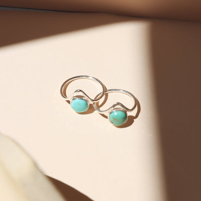 sterling silver rings with point and round turquoise stone on a light dish