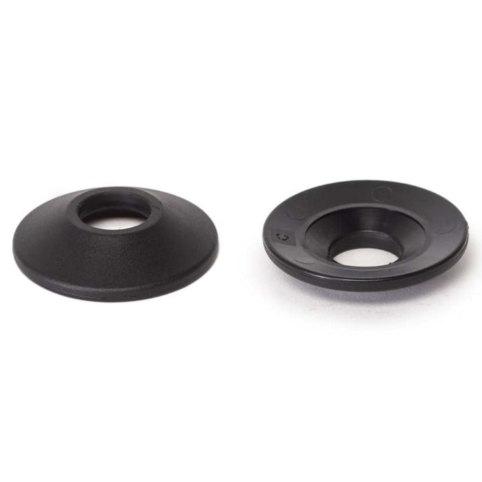 Two black, round plastic Wethepeople Helix Front Hub Guards with central holes rest on a white surface; one lies flat, while the other is slightly raised.