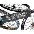 Three vibrant bicycle wheels with “STAY LUX” text and a banner overlay reading “BUILD YOUR DREAM WHEELS AND SAVE $$$ TODAY!” in bold white letters, showcasing the (Workshop) Spectre High Strength Wheel Build (36 Hole) with stainless steel spokes—enjoy 50% OFF LABOUR when you purchase a rim and hub.